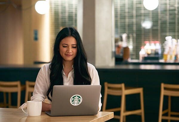 A person sits in front of an open laptop, focused on work, with a cup of coffee beside them